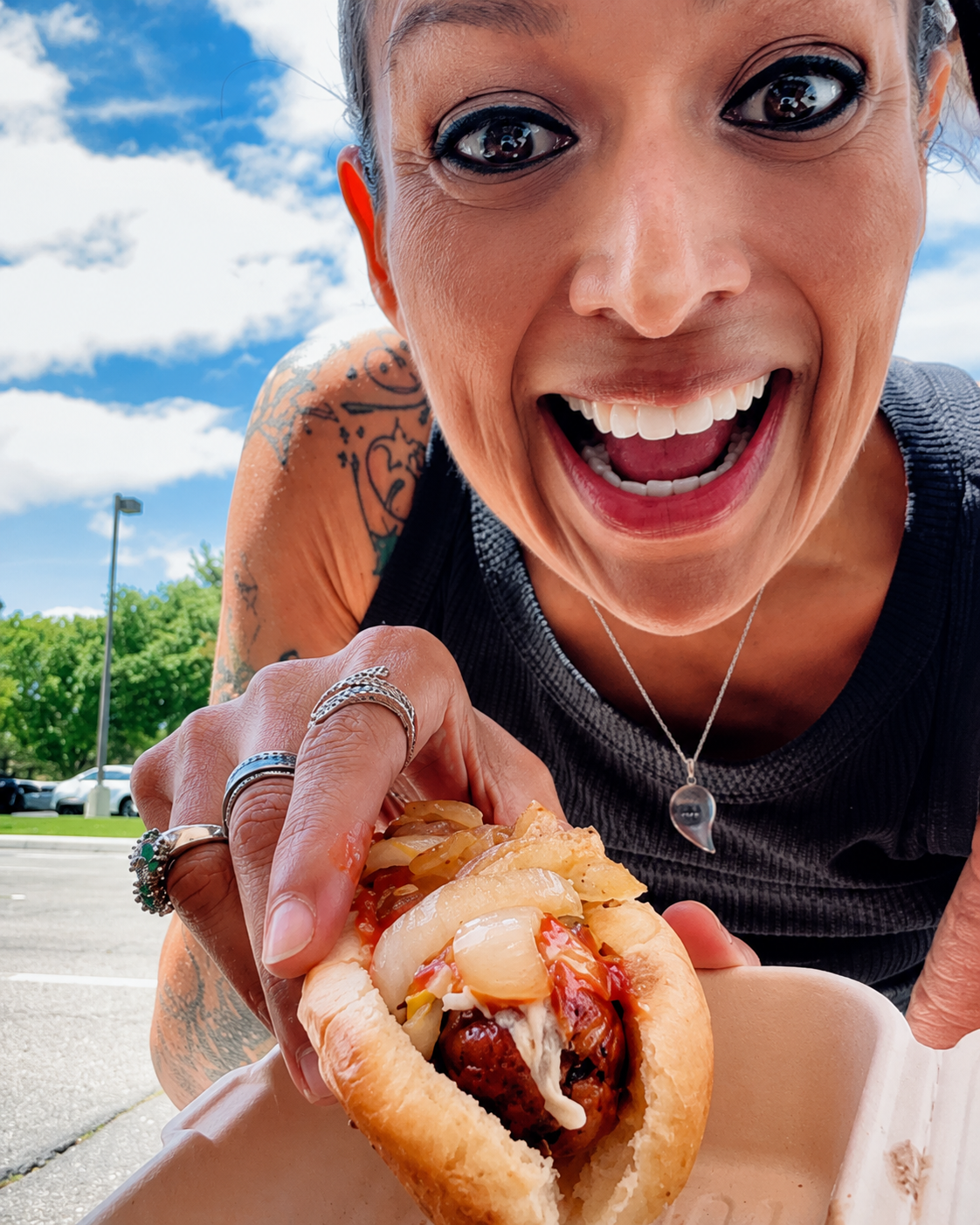 Happy customer holding a loaded What Up Dogz hot dog